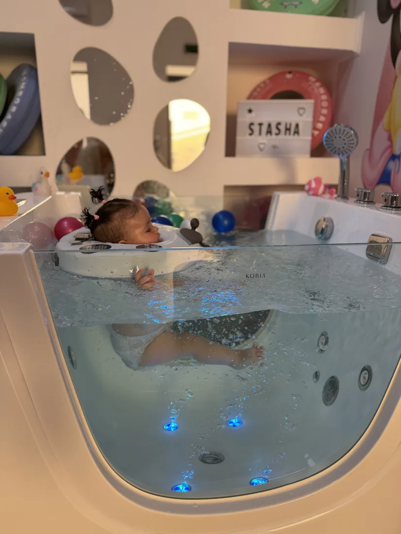 Vesela beba uživa u hidromasaži tople vode — baby spa Pančevo